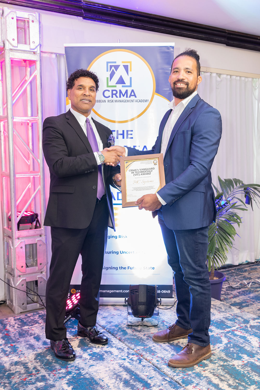 Dmitri Dawkins (r), Commercial Director, MC Systems Ltd. accepts the Vanguard in Technology (VIT) Award from Ken Hacksaw (l), Founder and President of the Caribbean Risk Management Academy (CRMA). The award was presented during the CRMA 6th Annual Hybrid Risk Management Conference held at the Jamaica Pegasus Hotel in Kingston, Jamaica.